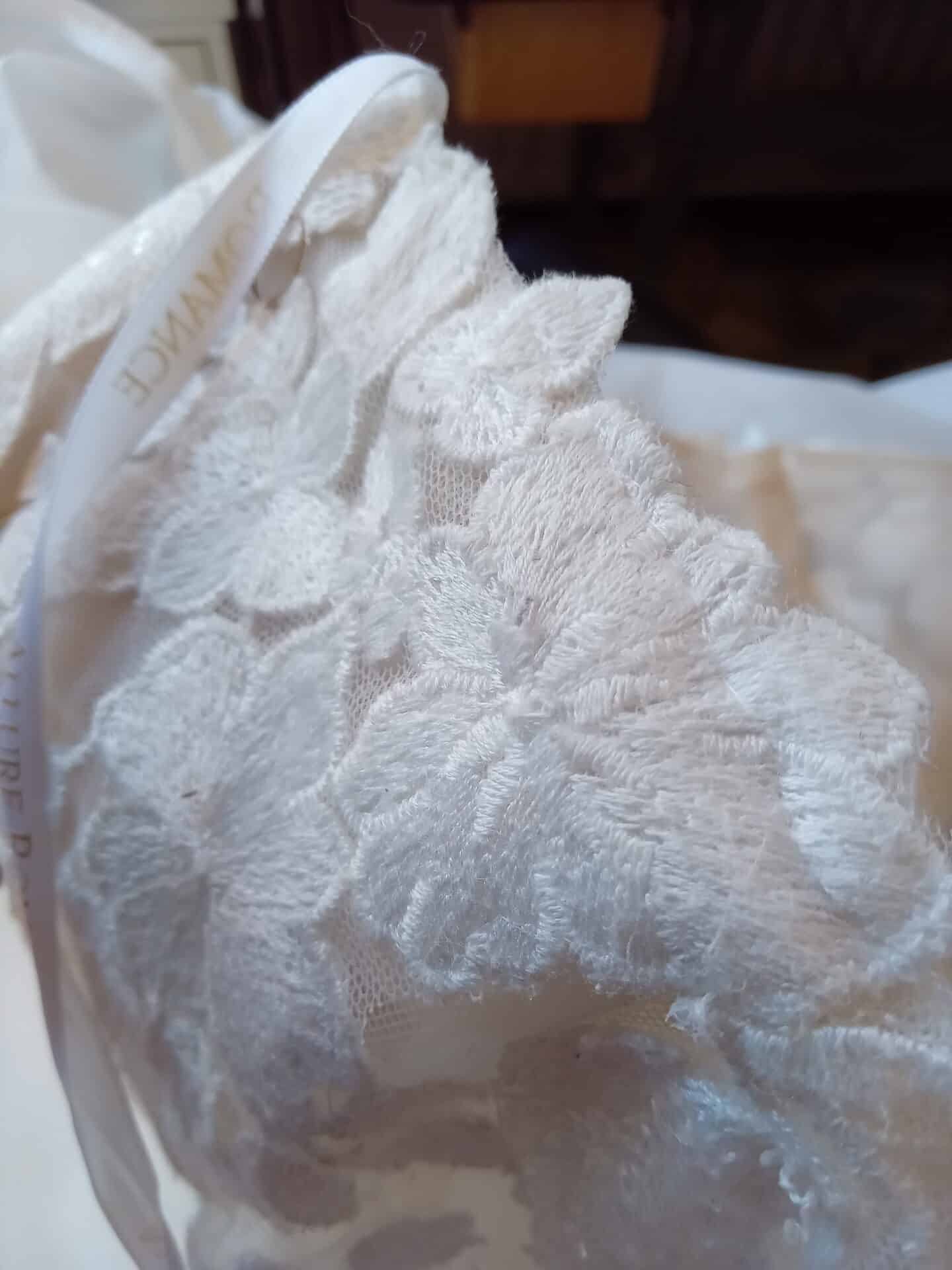 Close-up of white lace fabric with floral pattern and a white ribbon label.