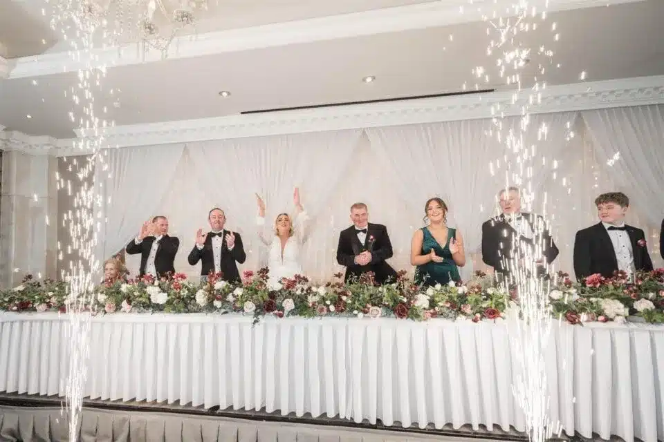 Wedding head table with guests celebrating under sparklers.