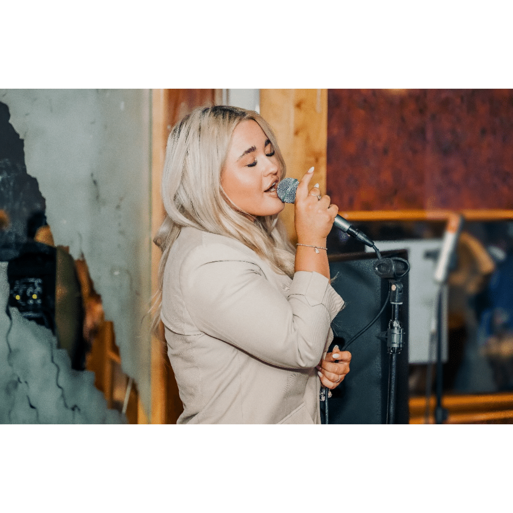 Woman singing into a microphone in a cozy indoor setting.