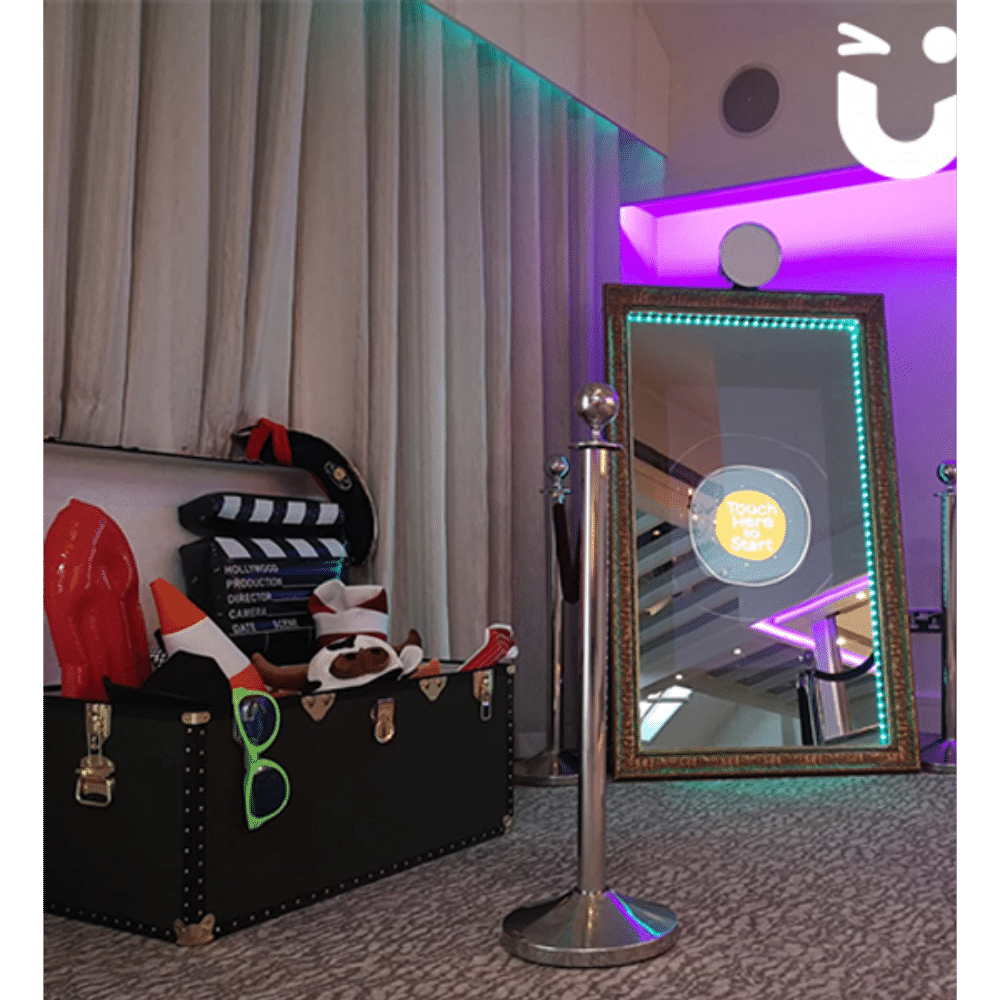 Magic selfie mirror setup with props, a rope stand, and colorful lighting in a decorated room.