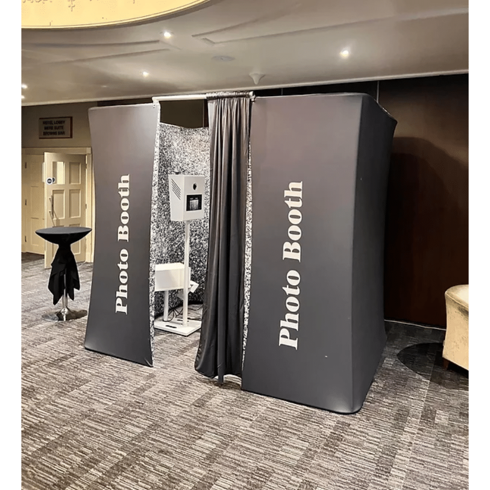 Photo booth setup in a spacious room with a black fabric exterior and a small table nearby.