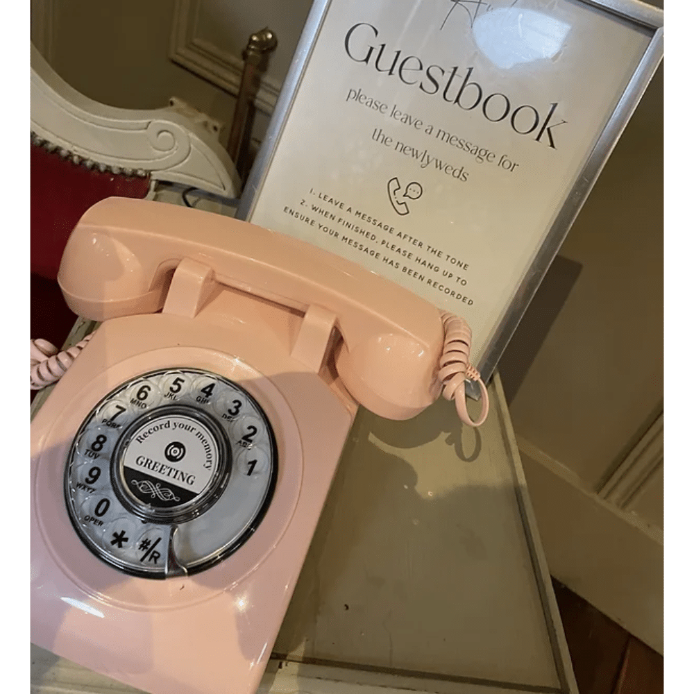 Pink rotary phone next to a guest book sign for leaving messages for newlyweds.