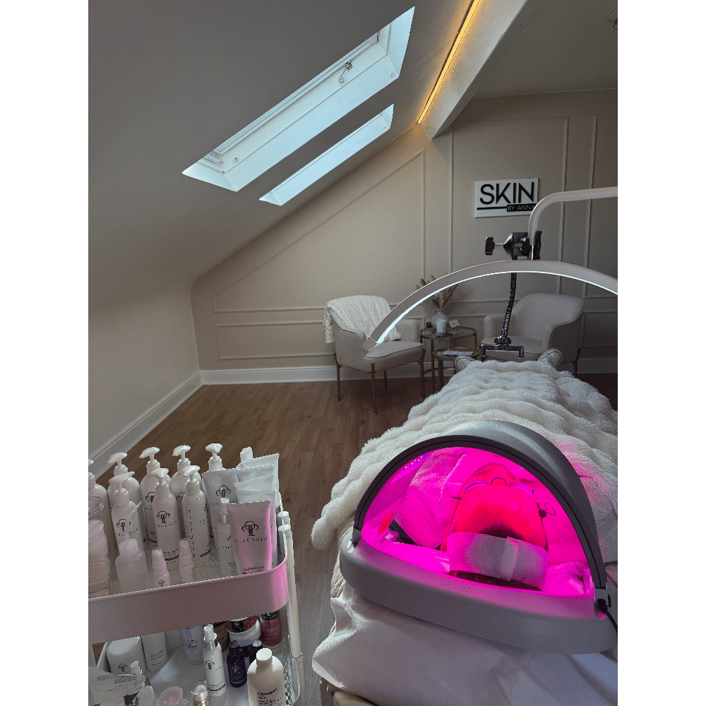 Spa room with skincare products, a treatment bed under LED light therapy, and cozy seating area.