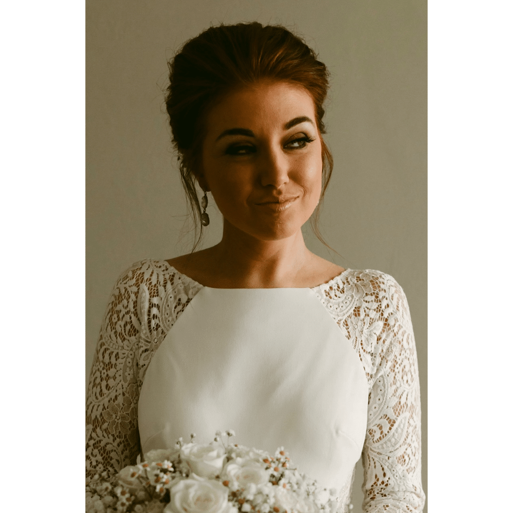 Bride in a lace wedding dress holding a bouquet of white roses.