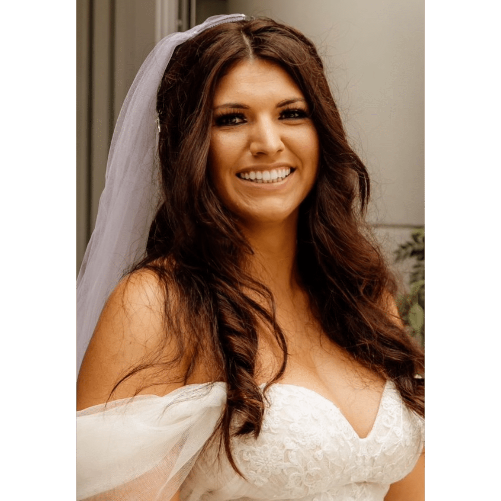 Smiling bride in a white wedding dress and veil.