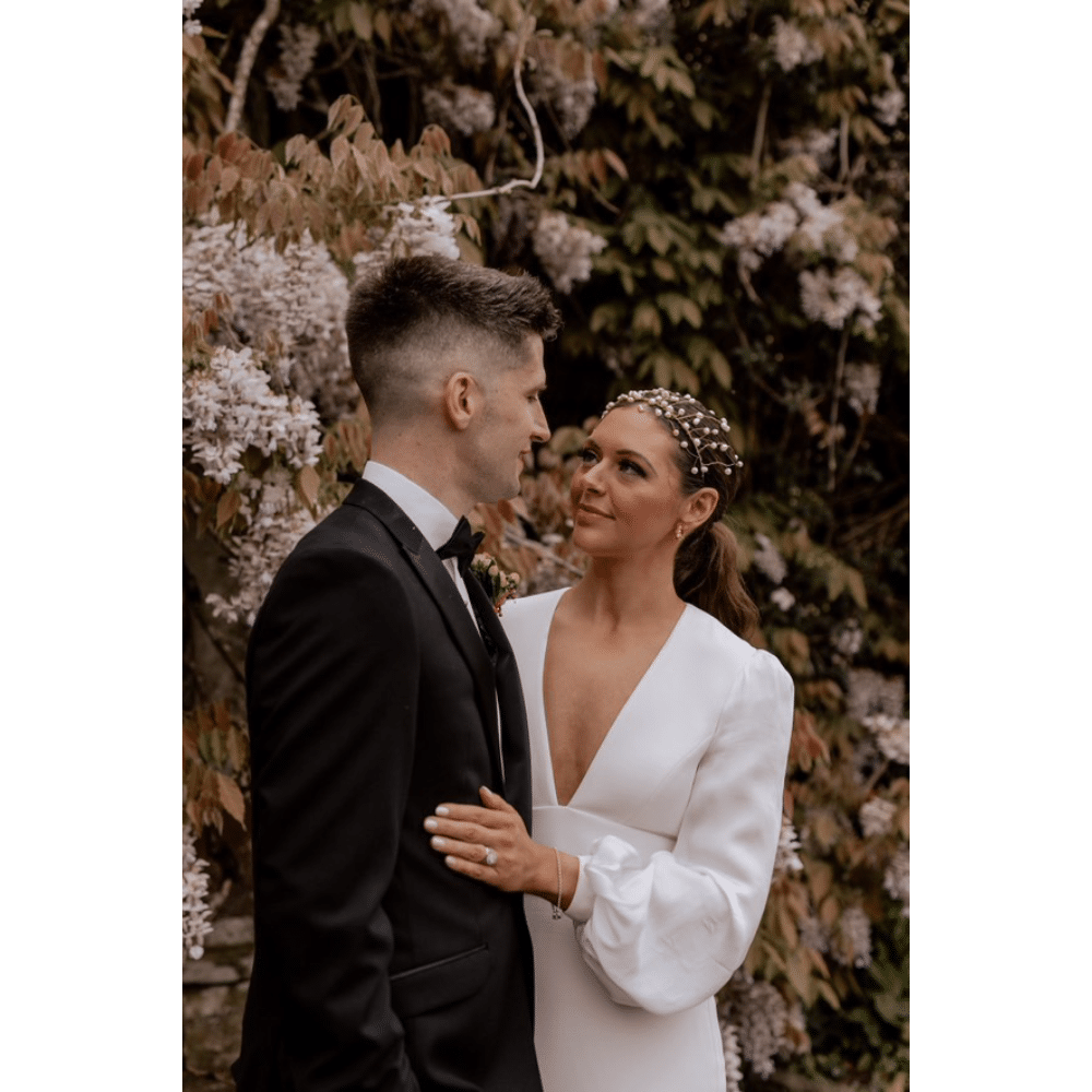 Bride and groom gazing at each other outdoors with floral background.