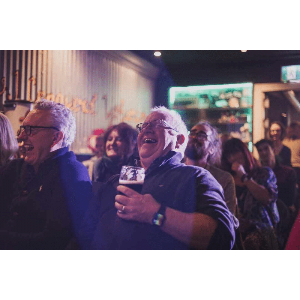 Group of people laughing and enjoying themselves at a lively indoor event.