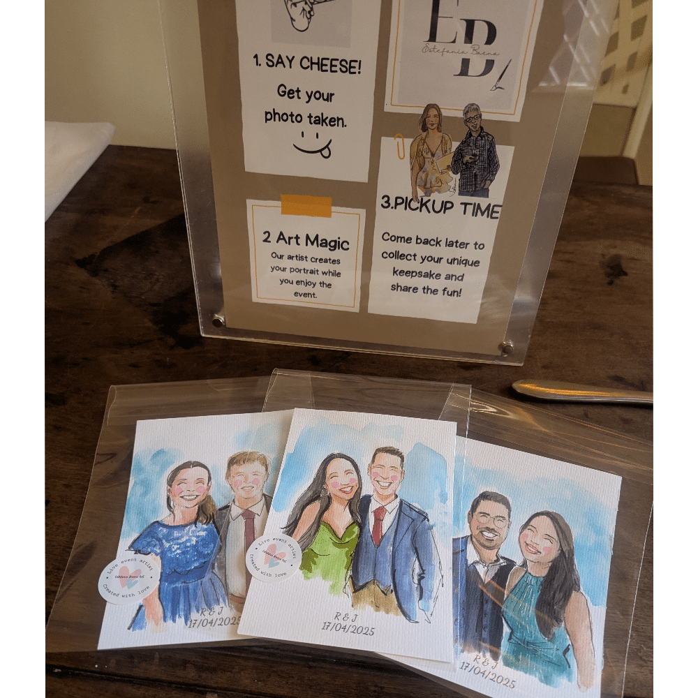 Display sign and three watercolor portraits on table at an event.