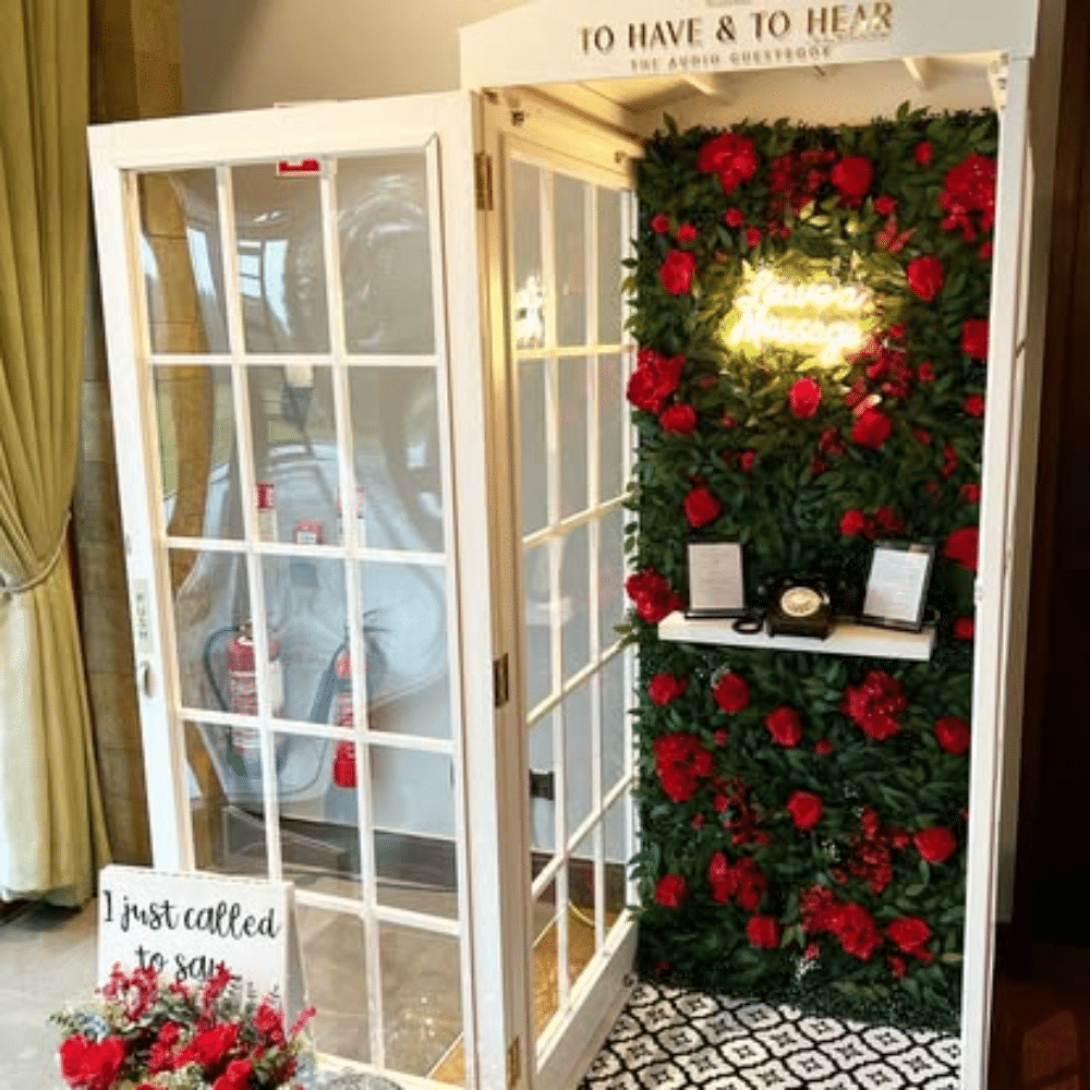 Wedding telephone booth guestbook with floral wall, vintage phone, and neon sign reading "Leave a Message."