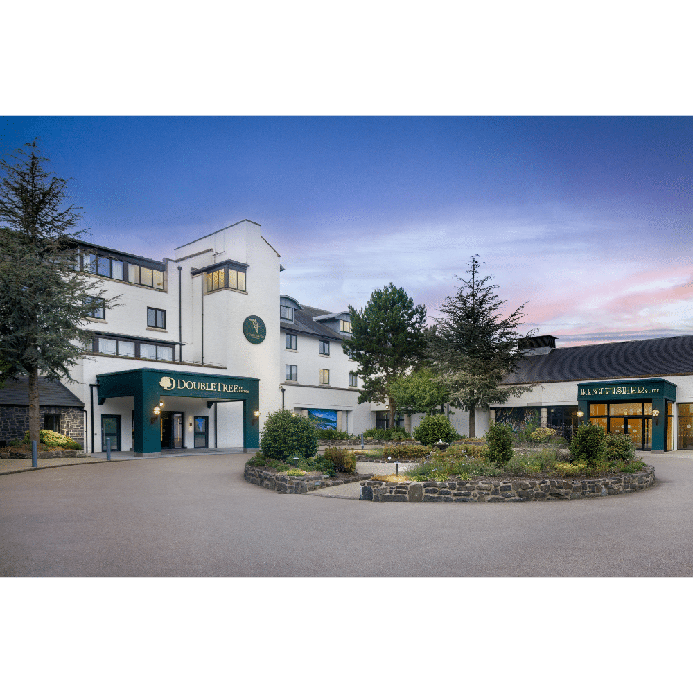Hotel with landscaped entrance and modern exterior at sunset.