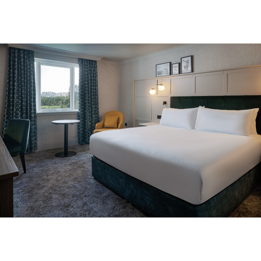 Stylish hotel room with a king-sized bed, modern decor, and a large window with a garden view.