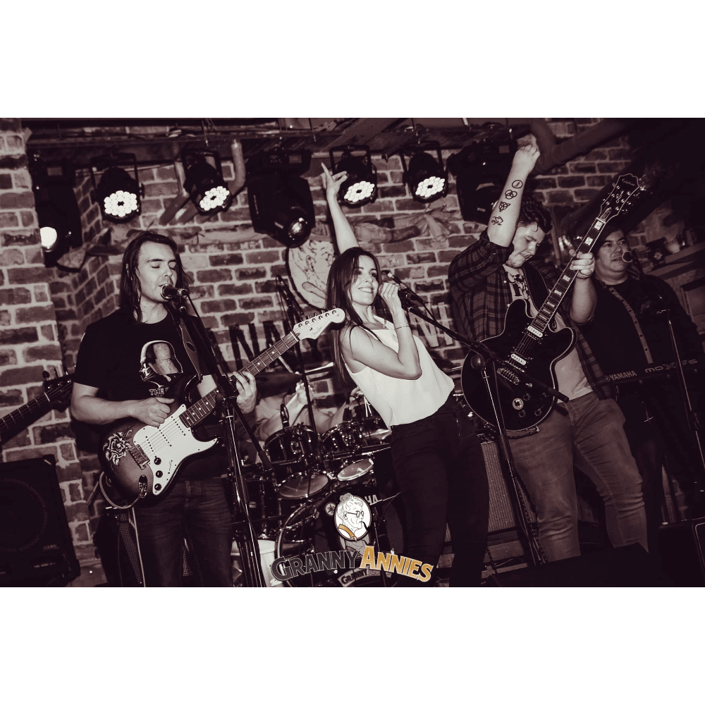 Band performing live on stage at Granny Annies, with guitarists and a singer.
