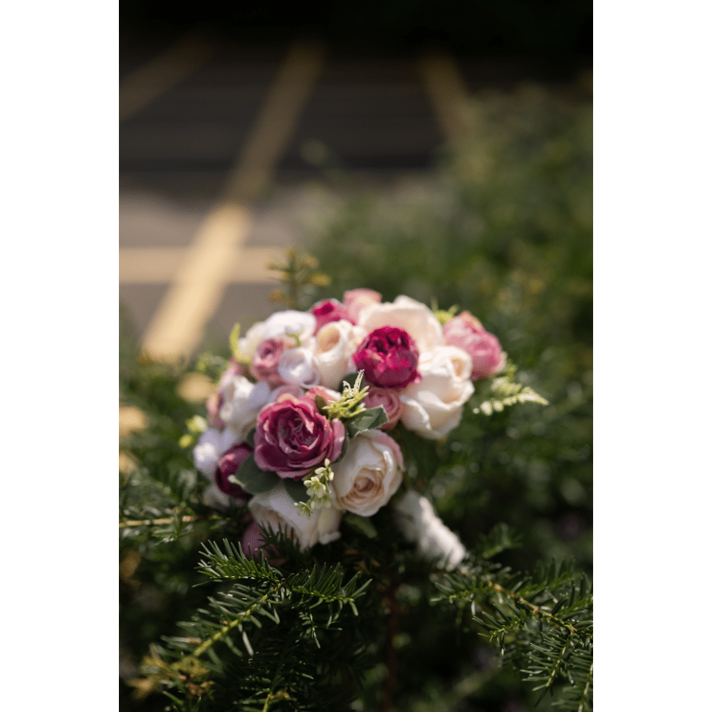 Bouquet of pink and white roses placed on green foliage with blurred background.
