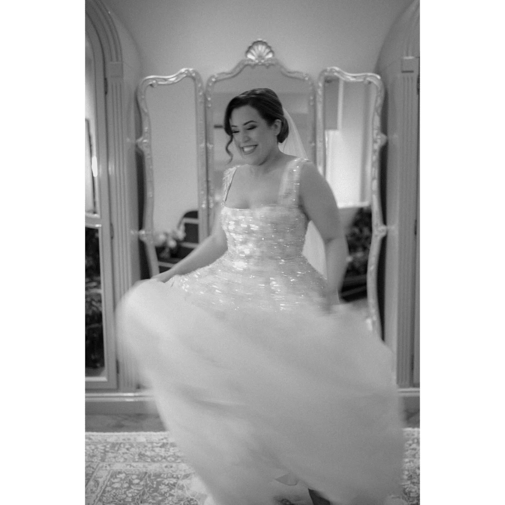 Bride joyfully twirls in a sparkling wedding dress, captured in black and white.