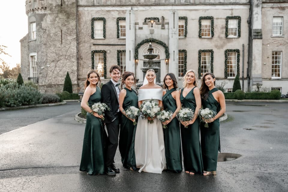 Wedding party in formal attire posing outside Bellingham Castle.