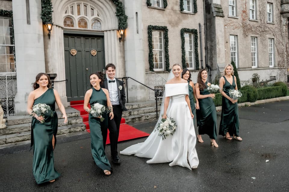 Bride, groom, and bridesmaids in elegant attire at a wedding outside Bellingham Castle.