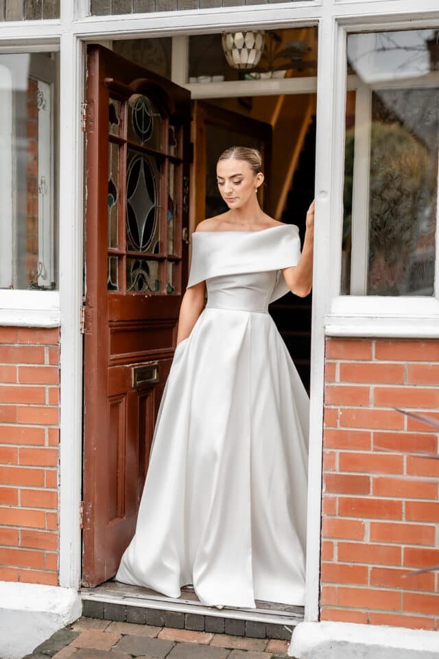 Bride in white gown standing in a doorway at Bellingham Castle.