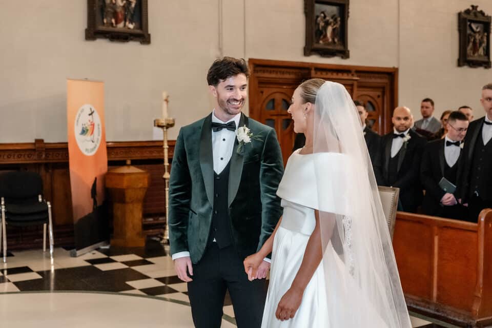 Bride and groom smiling at each other during wedding ceremony inside Bellingham Castle.