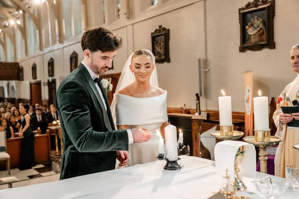 Bride and groom lighting unity candle at wedding ceremony in a church.