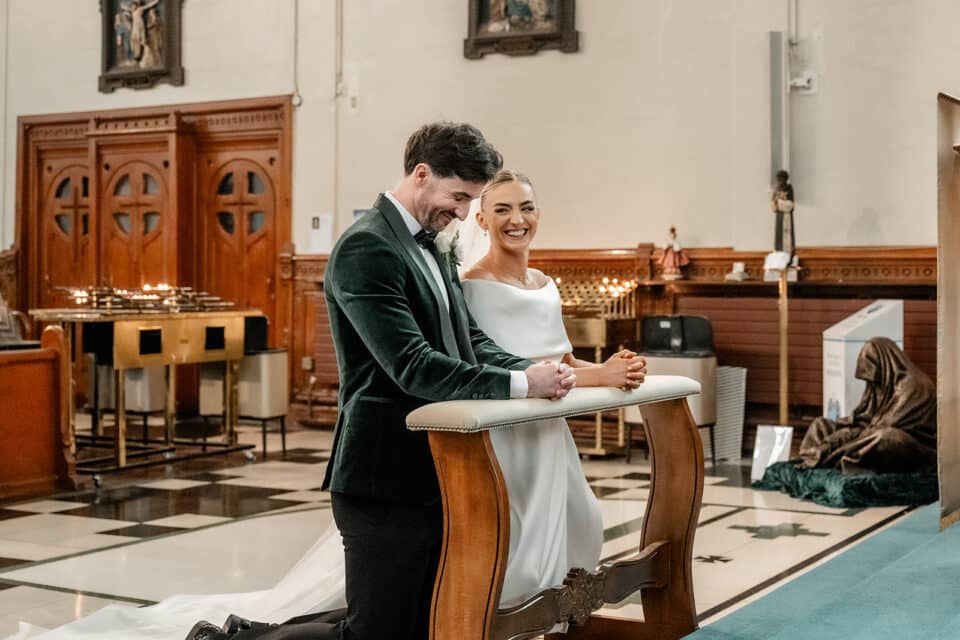 Bride and groom kneeling at the altar during a wedding ceremony in a church.