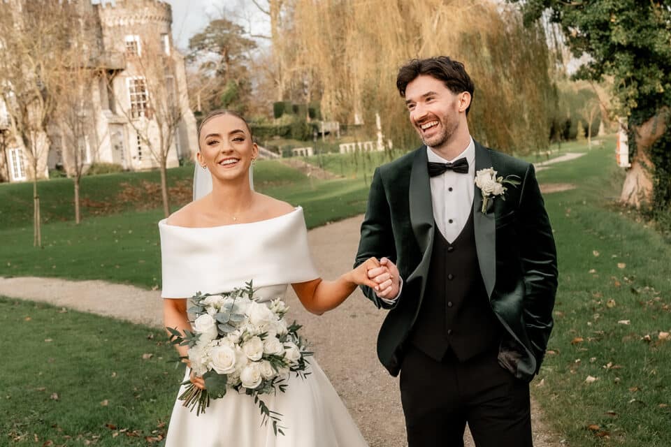 Bride and groom walking happily in a garden at Bellingham Castle.