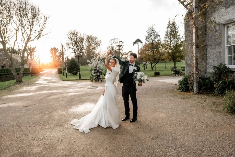 Bride and groom dancing outside Bellingham Castle at sunset.