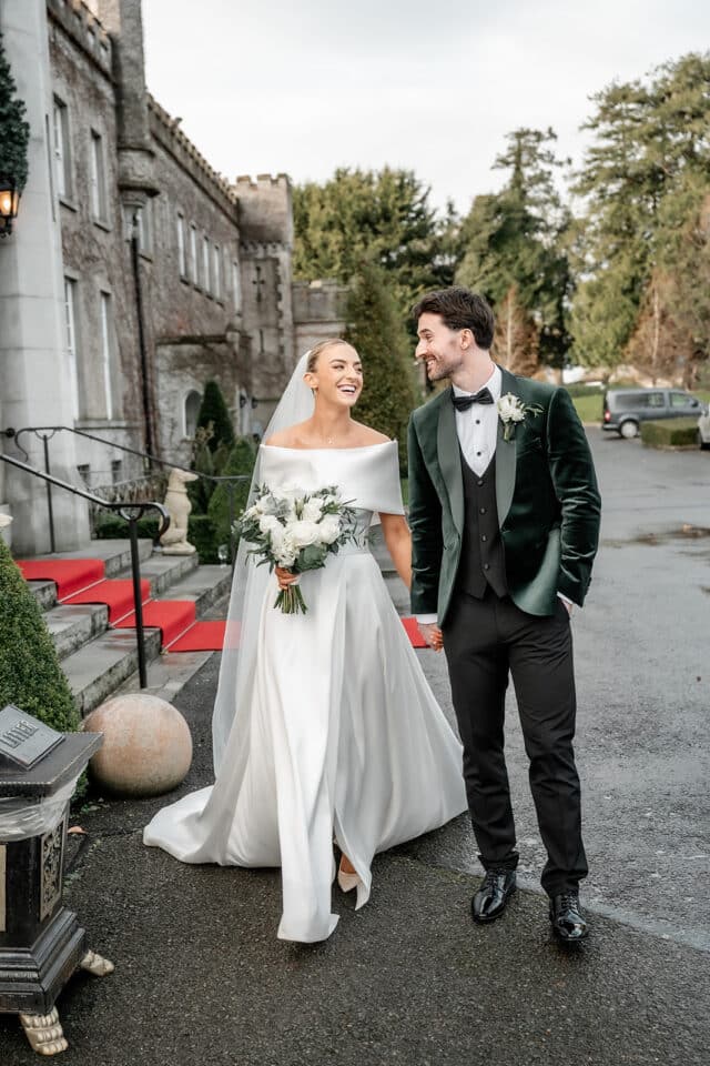 Bride and groom smiling and walking outside Bellingham Castle.