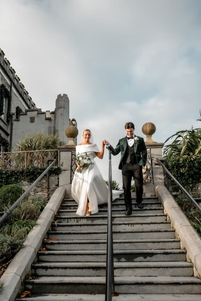 Bride and groom descending stone steps at Bellingham Castle.