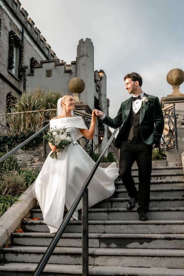 Bride and groom holding hands, descending stairs at Bellingham Castle.