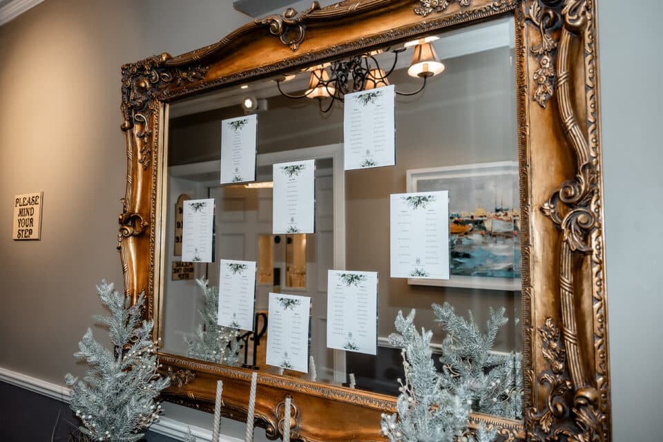 Elegant seating arrangement on a decorated mirror with holiday accents at a venue entrance.