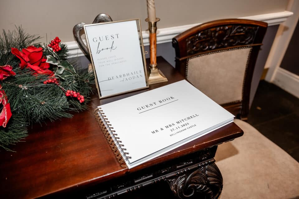 Wedding guest book table with floral decor and framed sign at Bellingham Castle.