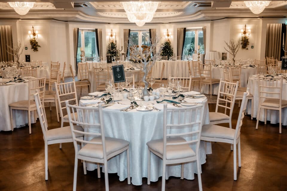 Elegant wedding reception setup at Bellingham Castle with round tables and white chairs.