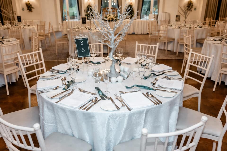 Elegant wedding reception table setup with silver tree centerpiece at Bellingham Castle.