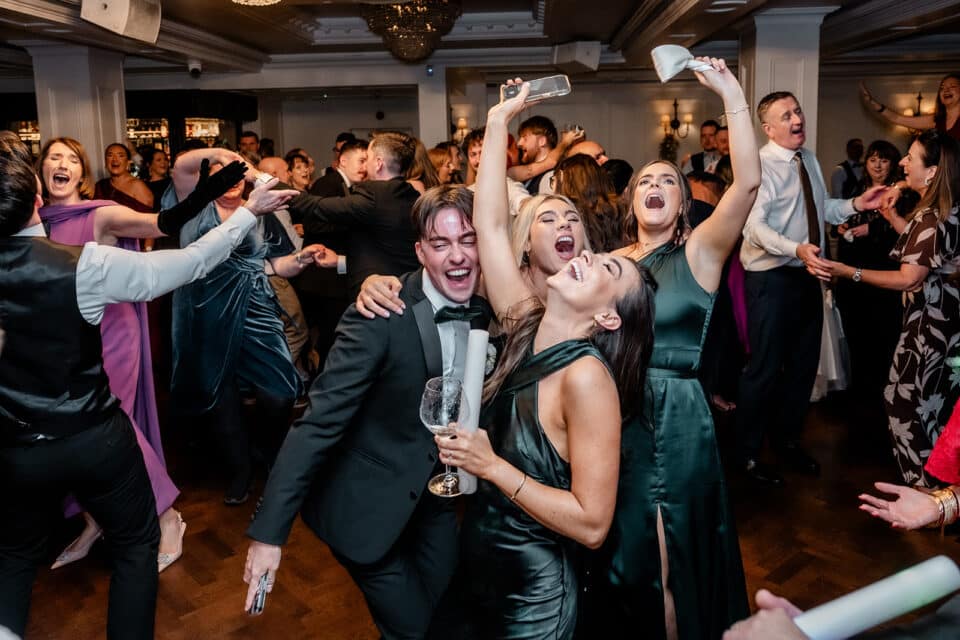 Guests dancing energetically at a wedding party at Bellingham Castle.