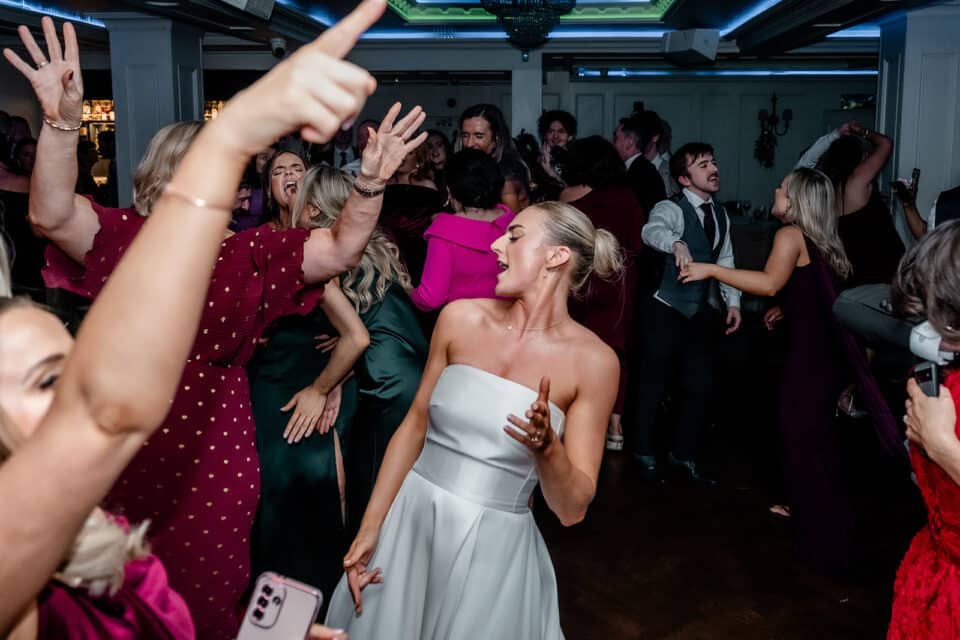 Guests dancing and celebrating energetically at a wedding reception in Bellingham Castle.