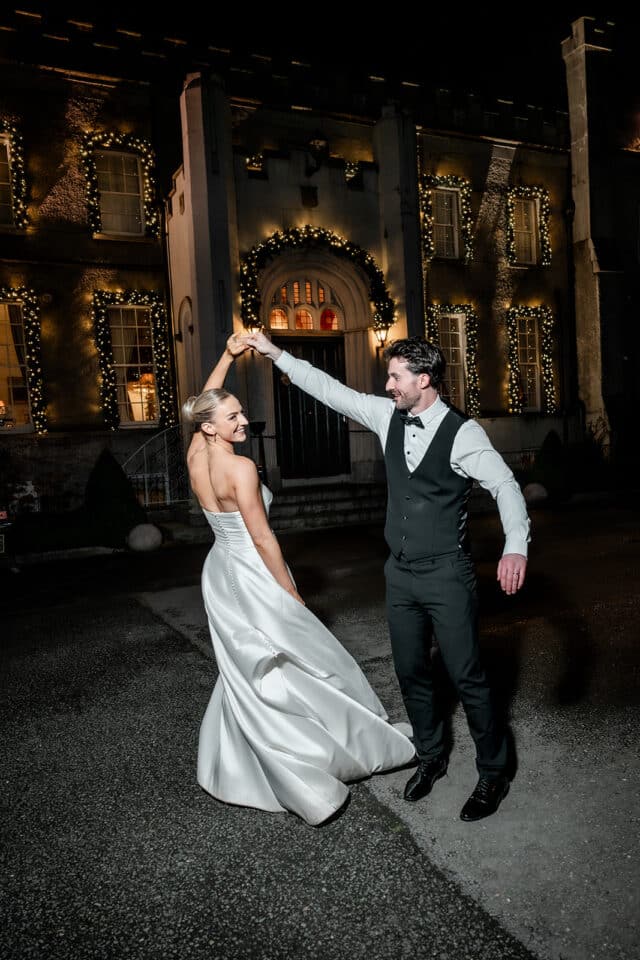 Couple dancing in front of illuminated Bellingham Castle at night.
