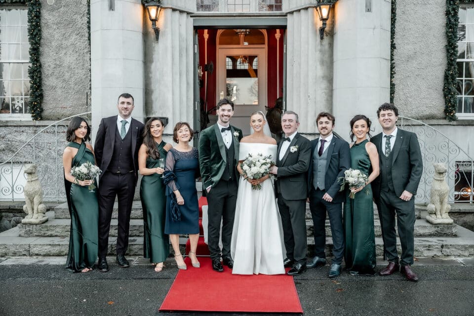 Wedding party posing on red carpet outside Bellingham Castle.