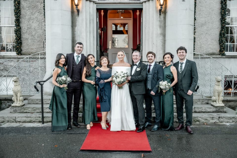 Wedding party posing on a red carpet in front of Bellingham Castle.
