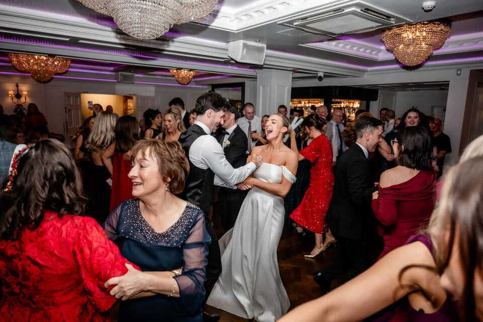 Wedding dance celebration at Bellingham Castle with a bride, groom, and guests joyfully dancing in an elegant ballroom setting.