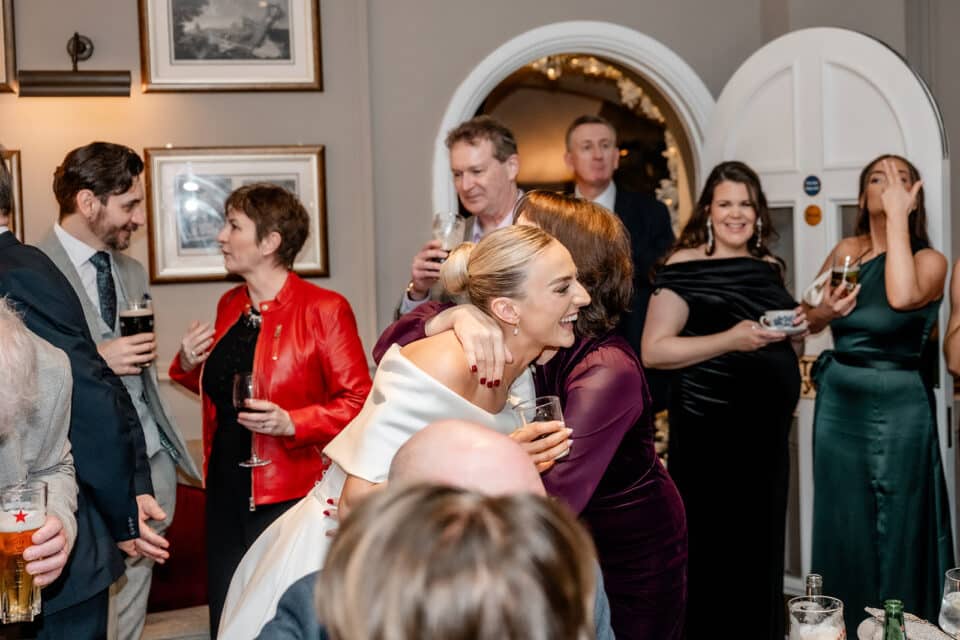 Joyful celebration at Bellingham Castle with guests hugging and chatting.