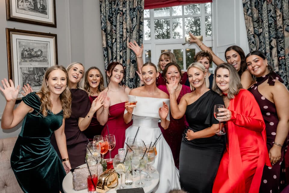 Bride and guests smiling and waving at a wedding reception at Bellingham Castle.