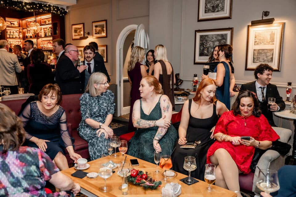 Guests mingling and socializing in a warmly lit room at Bellingham Castle, with drinks and festive decorations.
