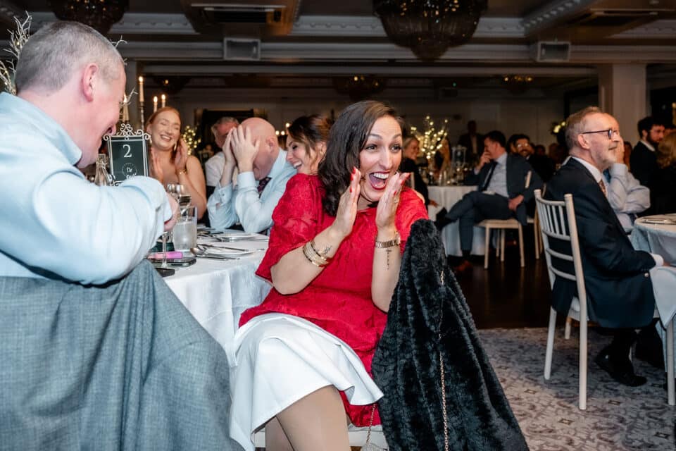 Guests laughing and clapping at a wedding reception in Bellingham Castle.