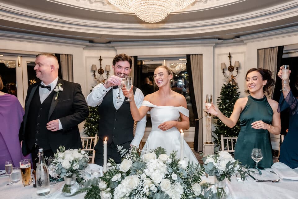 Wedding celebration at Bellingham Castle with guests toasting at a decorated banquet table.