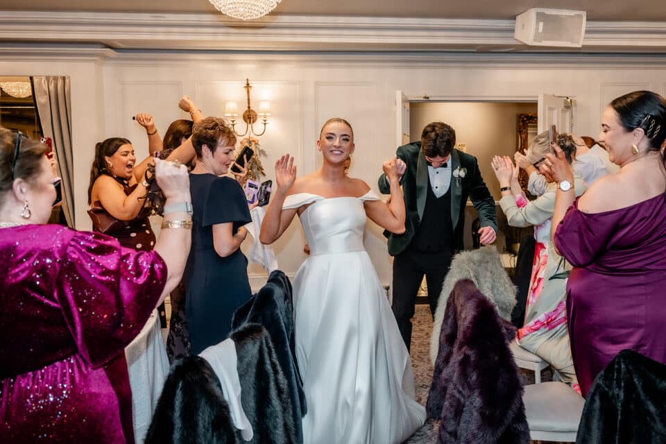 Bride and groom celebrating with guests indoors at Bellingham Castle.