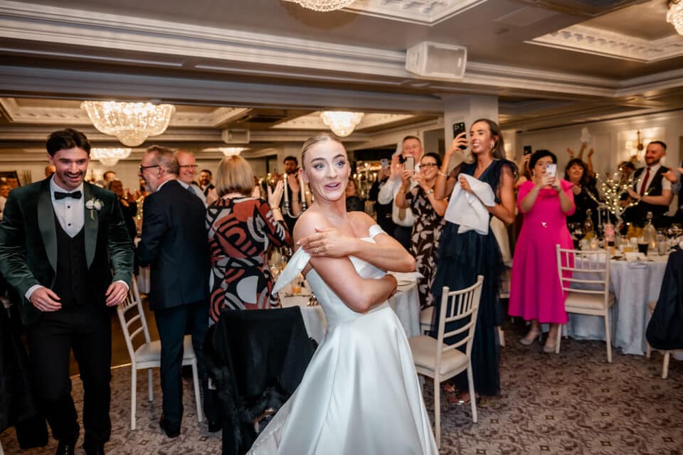 Bride and groom entering reception with guests applauding and capturing the moment at Bellingham Castle.