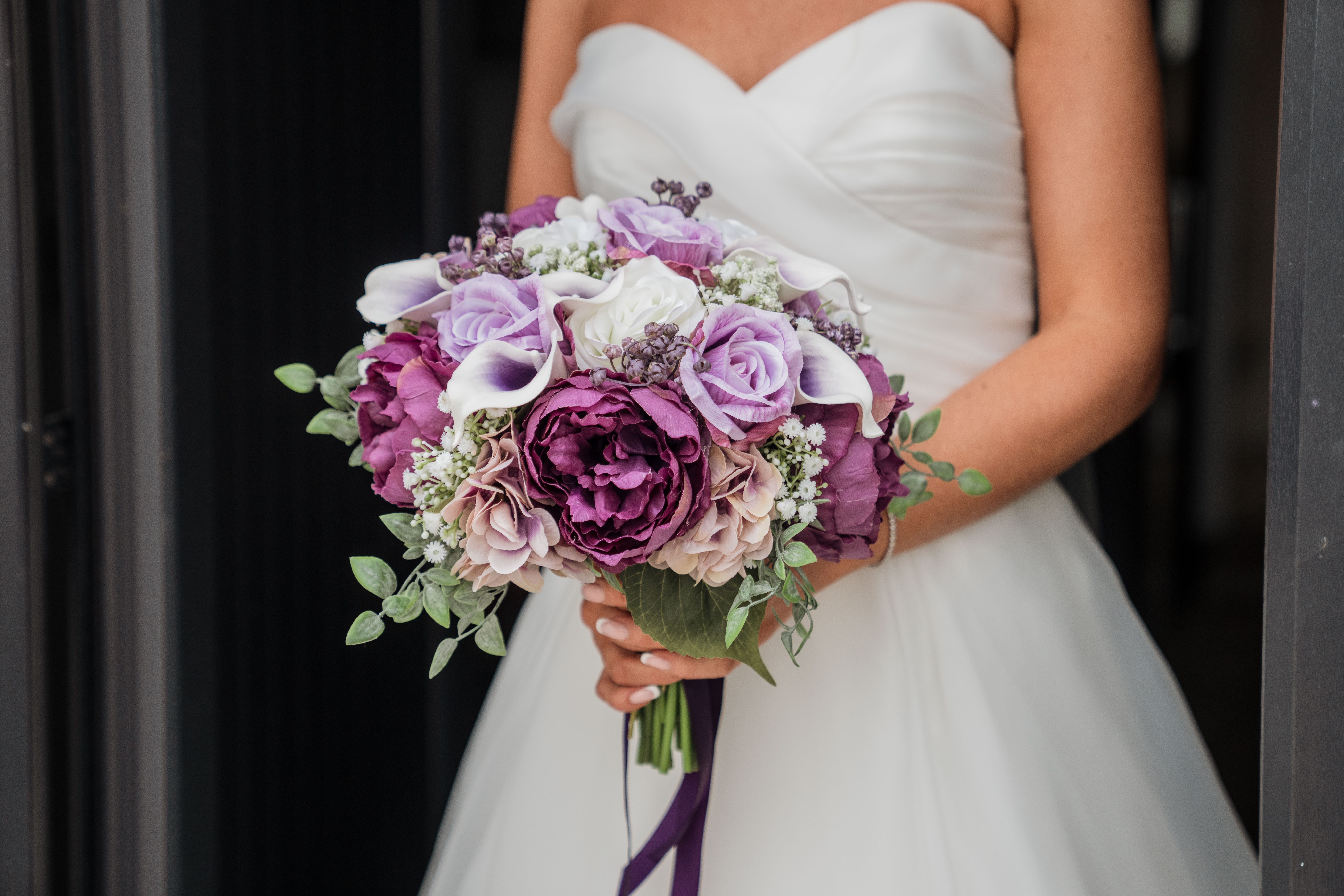 Bride holding a bouquet of purple and white flowers.