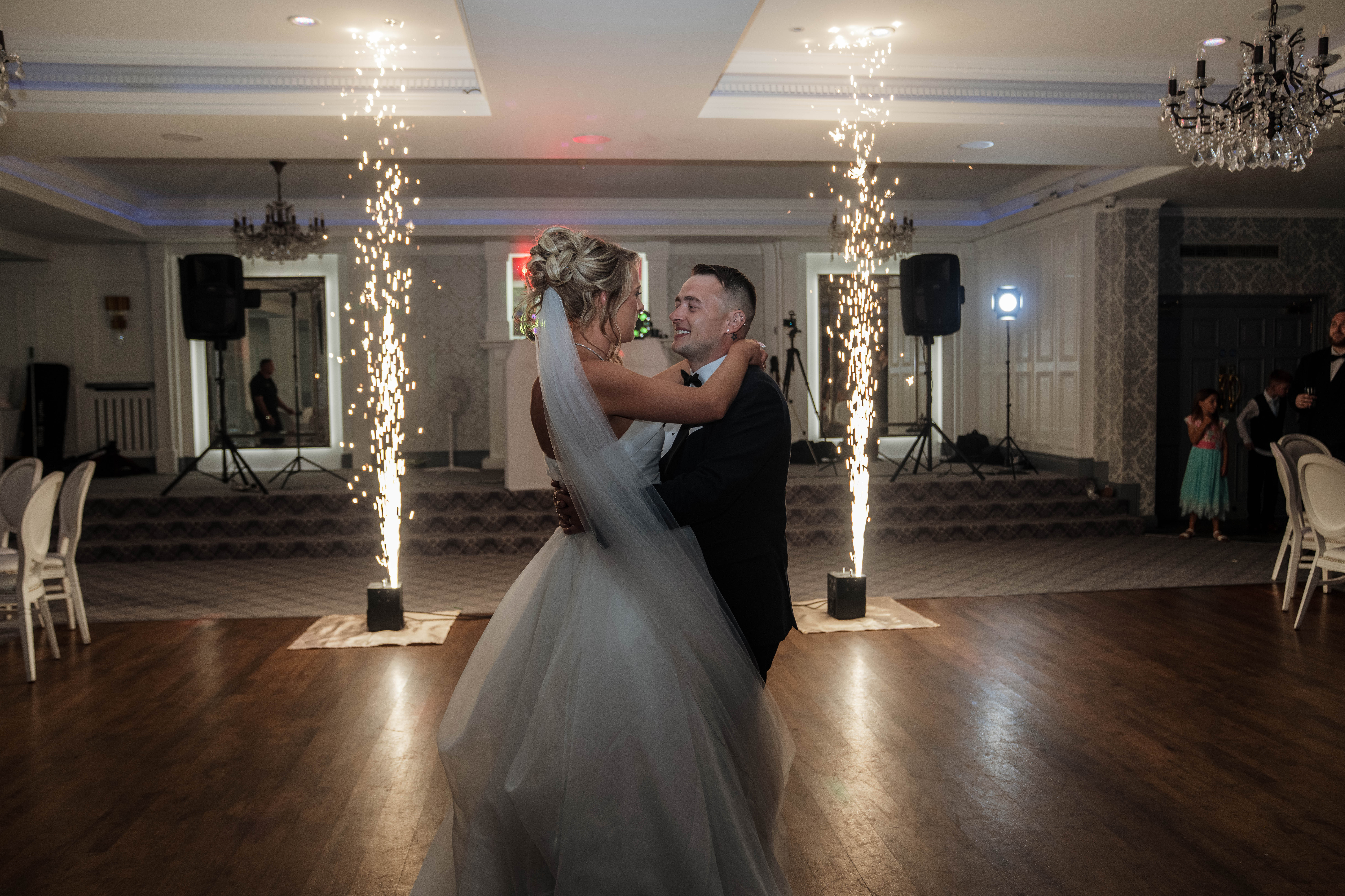 Bride and groom dancing with sparklers in background at wedding reception.