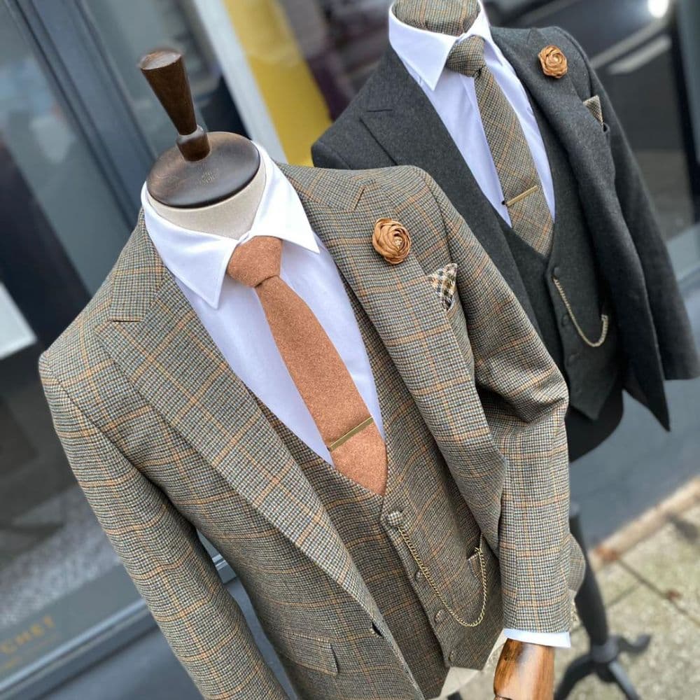 Two mannequins displaying tweed suits with ties and pocket squares.