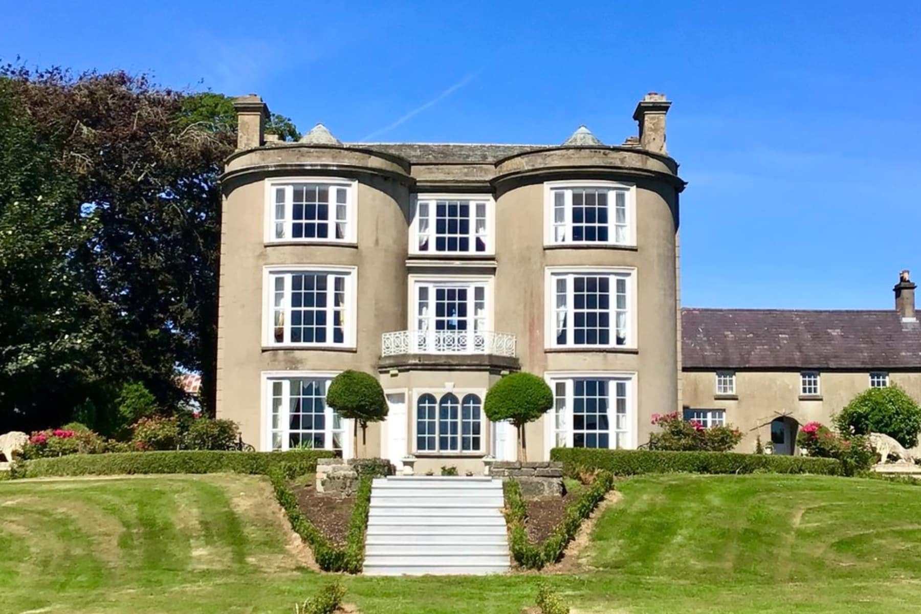 Gracehall venue with elegant windows, manicured lawns, and clear blue sky.